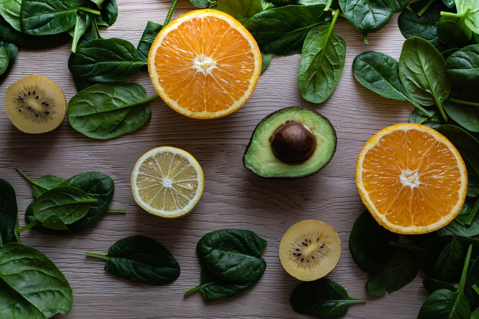 Espinafre, laranja, kiwi e abacate organizados sobre uma mesa